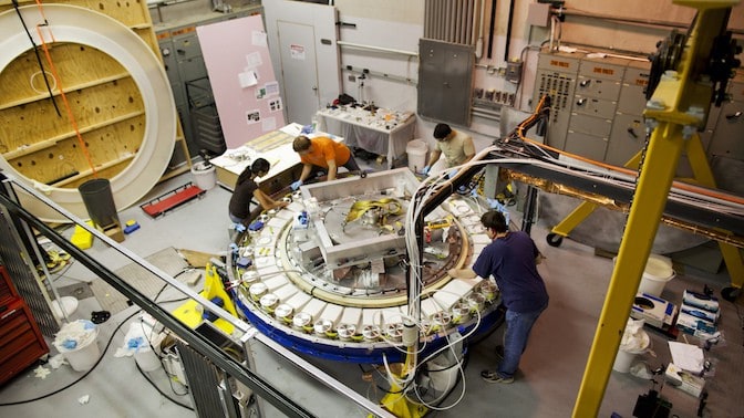 researchers working around a large circular piece of machinery