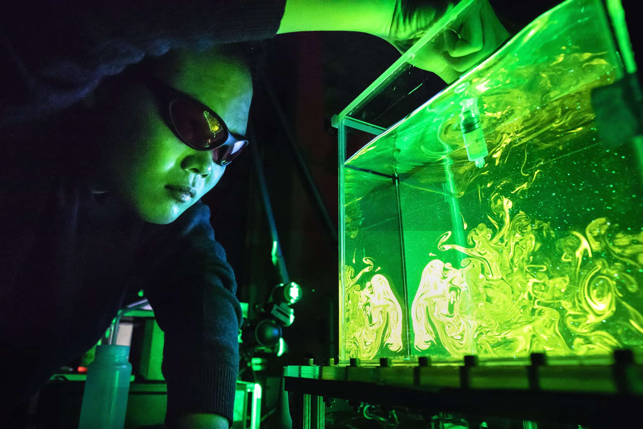 person in lab tooling with green glowing tank