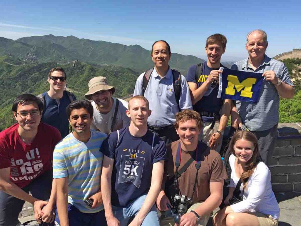 group of students at the Great Wall of China with a mini University of Michigan flag
