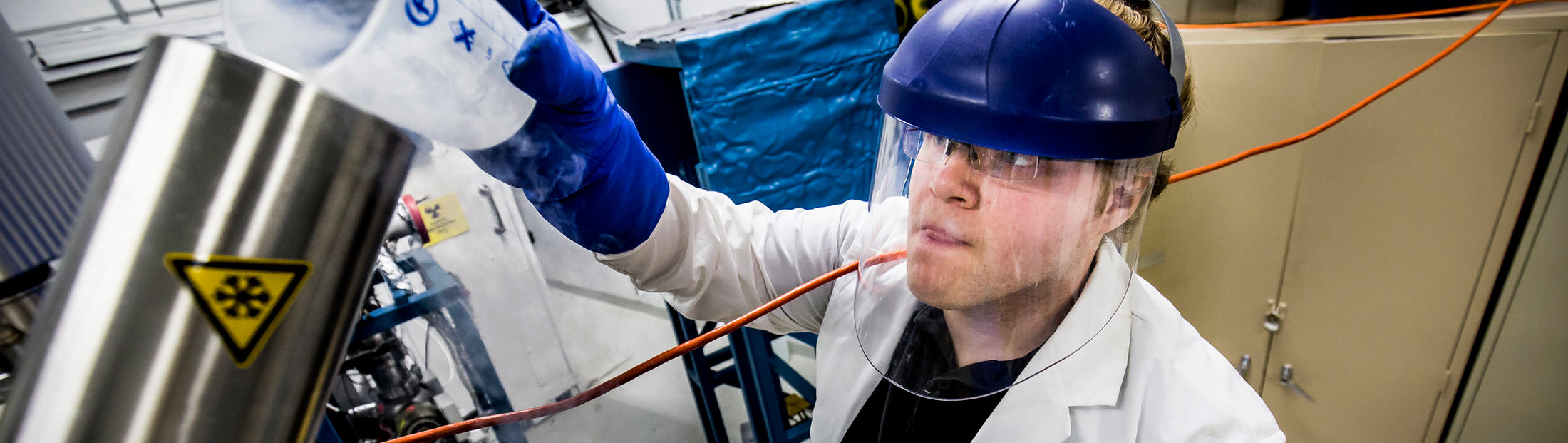 A student wearing safety gear working in a lab pouring liquids