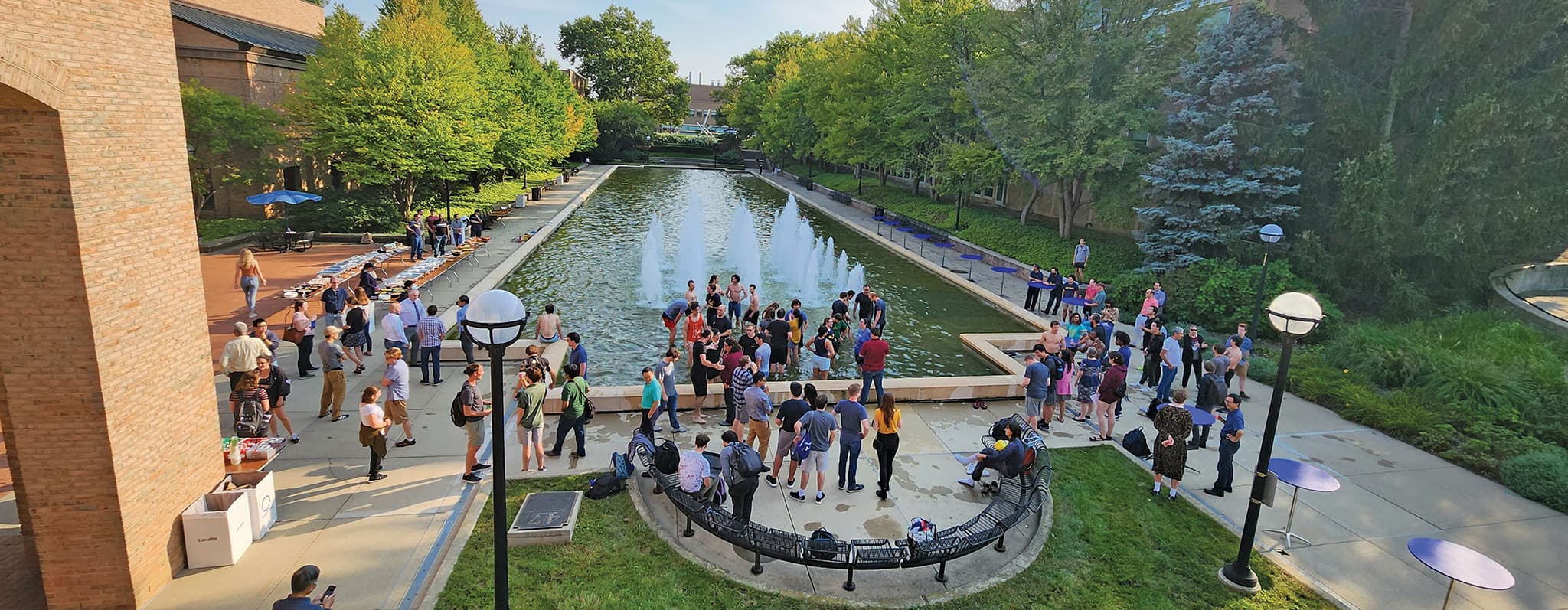 a large group of people standing around and in a fountain pond