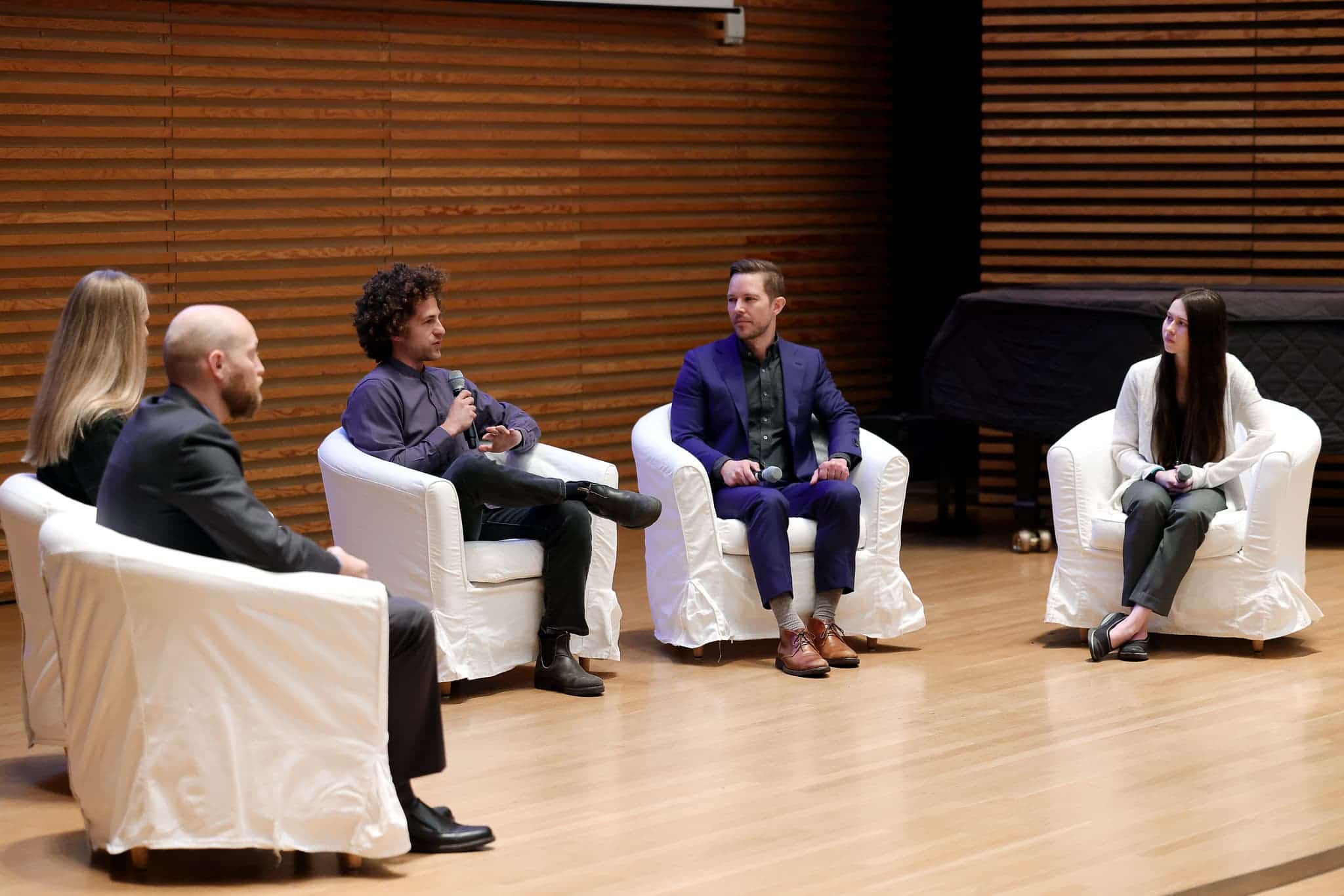 five people sitting on a stage having a discussion