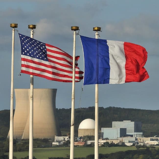 The flags of France and the USA in front of a nuclear facility.