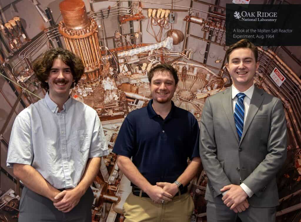 three men standing in front of a large piece of equipment