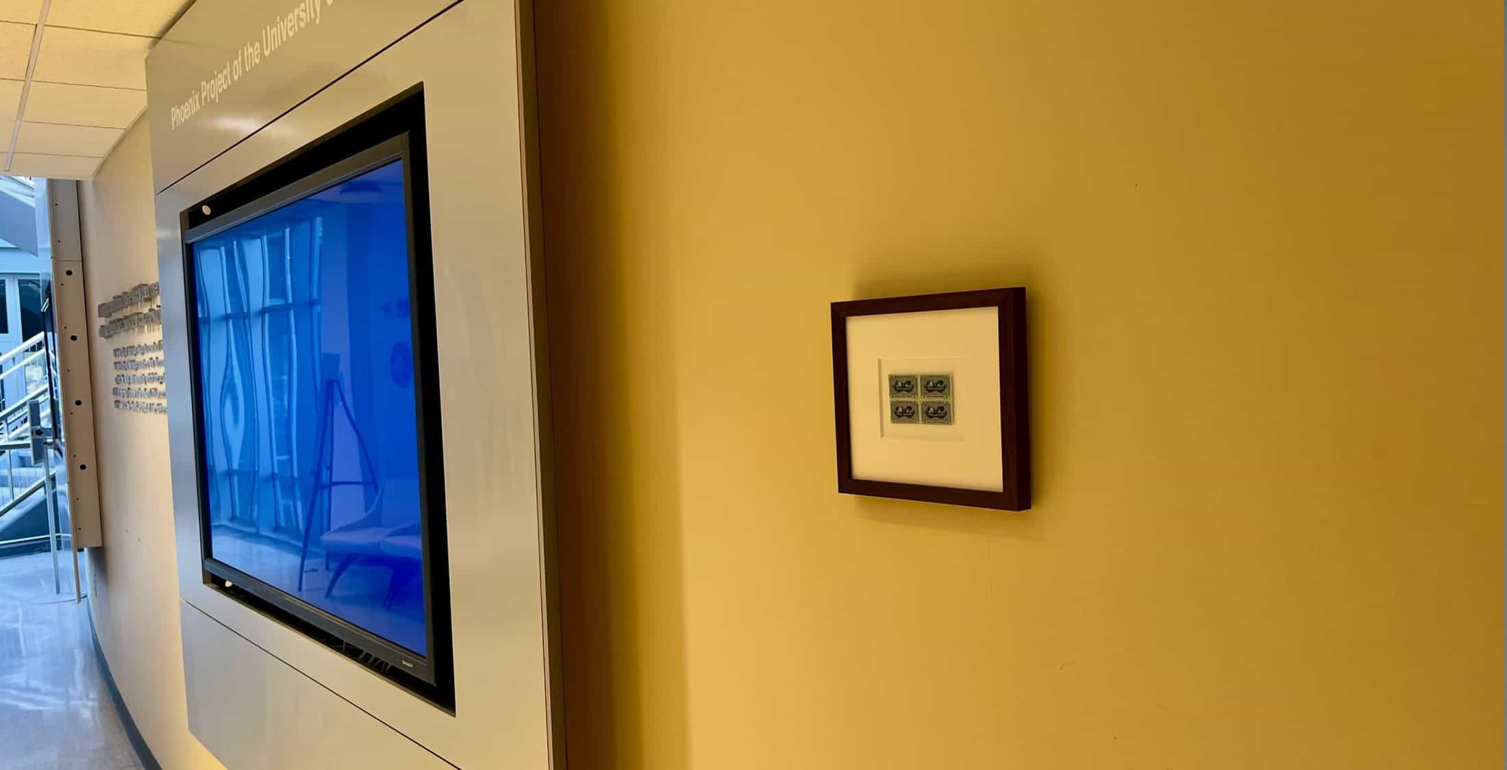 a television, a wall, and a framed set of stamps