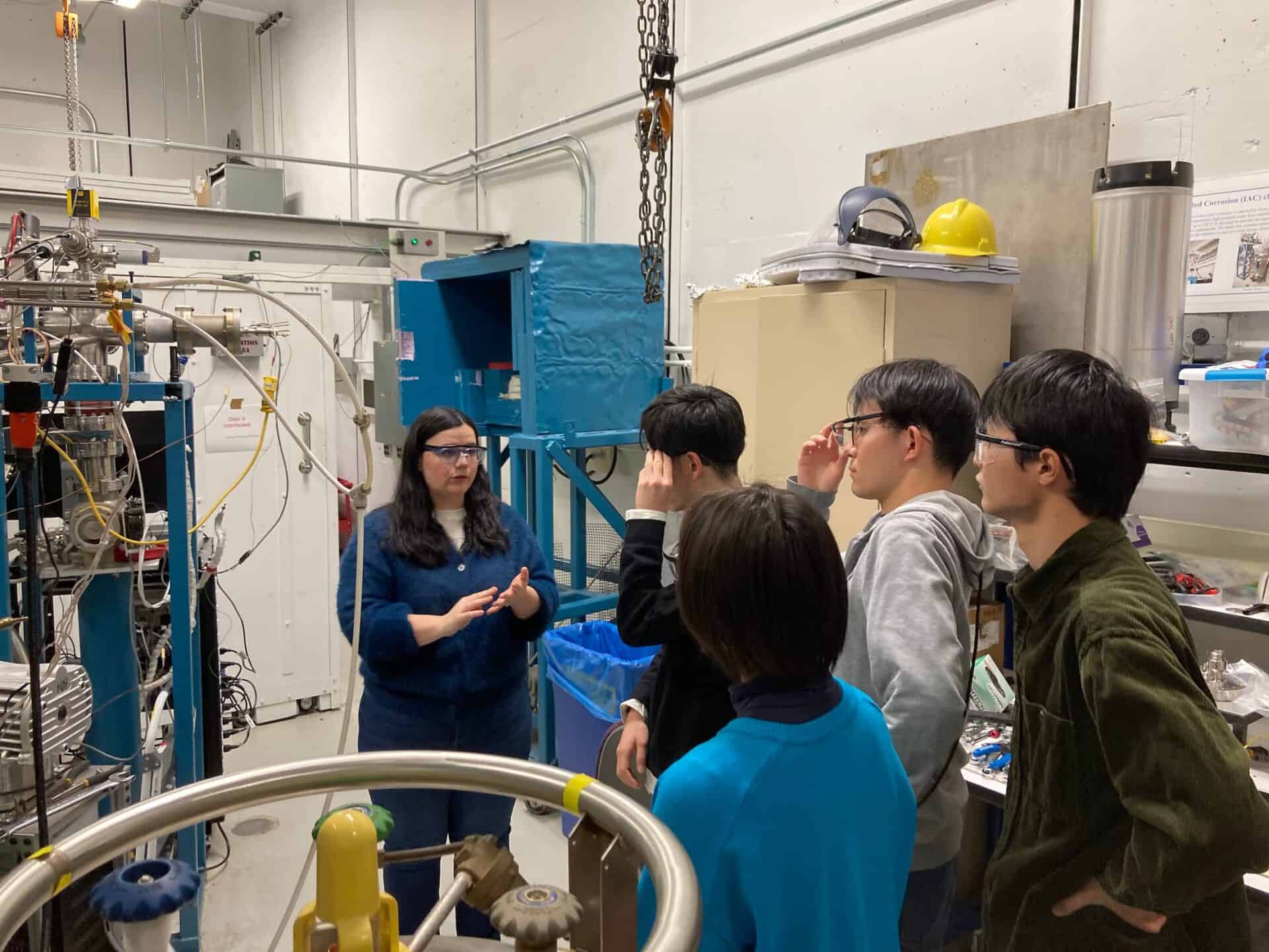 a woman speaking to a group of students in a laboratory